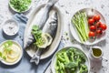 Set of healthy balanced ingredients for lunch - sea bass, asparagus, tomatoes, broccoli, green peas, olive oil and spices. On a li Royalty Free Stock Photo