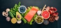 A set of healthy food. Fish, nuts, protein, berries, vegetables and fruits. On a black wooden background.