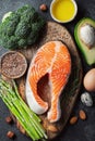 A set of healthy food for keto diet on a dark background. Fresh raw salmon steak with flax seeds, broccoli, avocado, chicken and Royalty Free Stock Photo