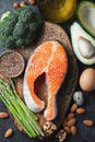 A set of healthy food for keto diet on a dark background. Fresh raw salmon steak with flax seeds, broccoli, avocado, chicken and Royalty Free Stock Photo