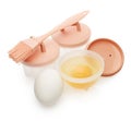 Set of heat resistant silicone molds for poached egg, basting brush and fresh raw eggs isolated on white background