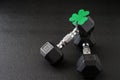 Set of hex head dumbbells with a green glitter shamrock on a black gym floor, happy St. Patrickâs Day