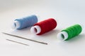 A set for hobbies and handicrafts. A set of multi-colored threads and needles for sewing close-up on a white fabric background