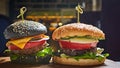 Set of homemade burgers in black and white buns with tomato, lettuce, cheese, onion on wood serving board over dark Royalty Free Stock Photo