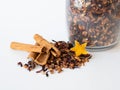 A set of ingredients for mulled wine is scattered on the table in front of a glass jar