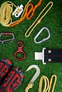 Set of items on the green lawn, to raise the mountains, ropes, carabiners of different models, shoes and safety belt.