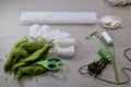 A set of items for needlework making snowdrops made of wool on a gray work surface, the front view at an angle