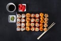 Set of Japanese rolls with salmon caviar and cheese on a black background top view, pickled ginger, wasabi, soy sauce, sticks Royalty Free Stock Photo
