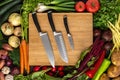 Set Kitchen Knives on Wooden Cutting Board with Fresh Vegetables Background. Healthy Eating Concept. Royalty Free Stock Photo