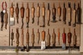 Set of leather craft tools hanging on the wall in workshop. Workplace for shoemaker. Various handmade shoemaking tools