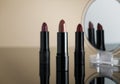 Set of lipsticks on cream reflective surface, two of them reflecting on a cosmetic mirror Royalty Free Stock Photo