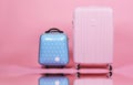 Set of luggage suitcase, Traveler pink suitcase and blue cabin size luggage on pink background.