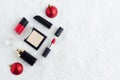 Set luxury cosmetics, red lipstick, nail polish, powder, perfume, balls on snow christmas background Royalty Free Stock Photo