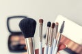 Set of makeup brushes in female hand on the background of eye shadow sets