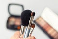 Set of makeup brushes in female hand on the background of eye shadow sets