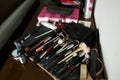 A set of makeup brushes in an open black cosmetic bag on a wooden table with cosmetics. Makeup artist set. Royalty Free Stock Photo