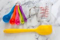 Set of measuring spoons made from colorful plastic, measuring cup made from glass and yellow silicone spatulas Royalty Free Stock Photo