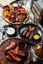 Set of meat dishes, fried sausages on a plate, grilled meat and pig ears with fries potatoes on cutting board, barbecue pork spare Royalty Free Stock Photo