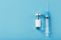 Ampoule with a vaccine and a syringe for viruses and diseases on a blue background