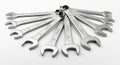 A set of metal combination wrenches is arranged in a fan shape on a white surface. Th Royalty Free Stock Photo