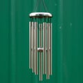 A set of metal wind chimes hangs against a solid green background. It consists of Royalty Free Stock Photo