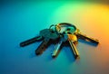 A set of metallic keys on a circular keyring placed on a smooth surface with a gradient of blue and green light