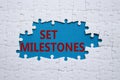 Set milestones symbol. Concept word Set milestones on white puzzle. Beautiful blue background. Business and Set milestones concept Royalty Free Stock Photo