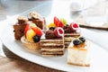 Set of mini cakes in assortment on white plate. Restaurant menu. Chocolate cake with raspberries. Tartlet with fruits. Royalty Free Stock Photo