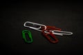 A set of multi-colored office paper clips of plastic are scattered on black monophonic background. Royalty Free Stock Photo