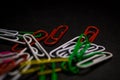 A set of multi-colored office paper clips of plastic are scattered on black monophonic background. Royalty Free Stock Photo