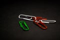 A set of multi-colored office paper clips of plastic are scattered on black monophonic background. Royalty Free Stock Photo