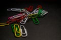 A set of multi-colored office paper clips of plastic are scattered on black monophonic background. Royalty Free Stock Photo