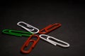 A set of multi-colored office paper clips of plastic are scattered on black monophonic background. Royalty Free Stock Photo