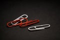 A set of multi-colored office paper clips of plastic are scattered on black monophonic background. Royalty Free Stock Photo