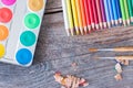 Creativity: Multi-colored pencils, water colors and brushes on rusty wooden table Royalty Free Stock Photo