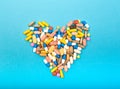 Set of multi-colored tablets and capsules on a blue background heart shape Royalty Free Stock Photo