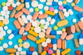 Set of multi-colored tablets and capsules on a blue background Royalty Free Stock Photo