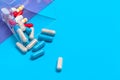 Set of multi-colored tablets and capsules on a blue background Royalty Free Stock Photo