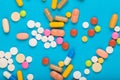 Set of multi-colored tablets and capsules on a blue background Royalty Free Stock Photo