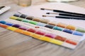 Set of multicolored watercolor palette and brushes on wooden table. Selected focus Russia, Omsk, April 2020
