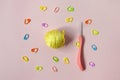 Set for needlework, knitting - crochet hook, ball of yellow thread with plastic needle and colorful pins on pink background.