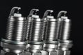 A set of new spark plugs of the car, and spare parts of vehicles on a dark background Royalty Free Stock Photo