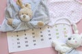 Set of newborn accessories in anticipation of child - calendar with circled number 21 twenty one, baby clothes, toys on pink