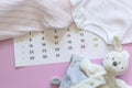 Set of newborn accessories in anticipation of  child - calendar with circled number 26 twenty six, baby clothes, toys on pink Royalty Free Stock Photo