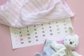Set of newborn accessories in anticipation of child - calendar with circled number 22 twenty two, baby clothes, toys on pink