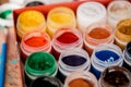 Set of nine colors gouache paints in jars on wooden table. Focus on red Royalty Free Stock Photo