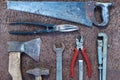 Set of old construction tools: hammer, saw, pliers, etc. on a flat lay background of rusty metal. Royalty Free Stock Photo