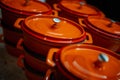 Set of orange pots with a cover for hot dishes close up with the dim background. clouse up