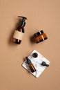 Set of organic cosmetics on brown background. Amber glass bottle with lotion, jar of natural cream, dropper bottle of essential