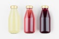 Set of organic fruits juices - pineapple, strawberry, pomegranade in glass bottles on white wood background, mock up for design. Royalty Free Stock Photo